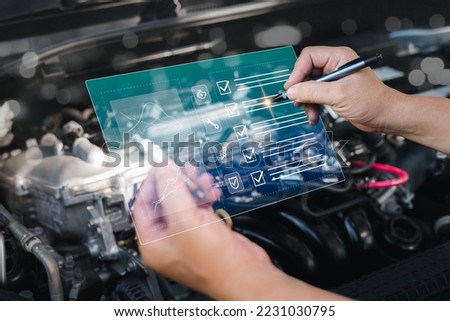 Technician using a pen checkbox on smart document about fault analysis from a virtual screen of a car and holding a broken spark plug in his hand to check and replace parts,engine room background Royalty-Free Stock Photo #2231030795
