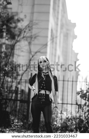 Portrait of a young and skinny model with long blonde and black hair and black clothes in the park in the afternoon (in black and white)