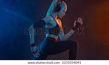 Strong athletic fit woman on black with neon lights background wearing in the sportswear. Fitness and sport motivation.