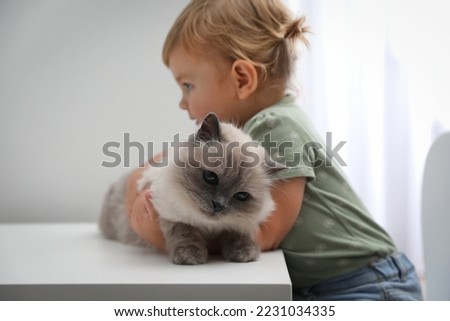 Cute little child with adorable pet at white table in room