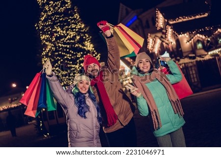 Photo of three overjoyed funky fellows hands hold raise shop bags enjoy christmastime buy souvenirs city center outside