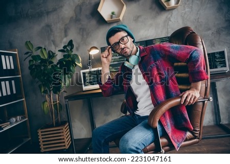 Photo of cool confident sound producer dressed hat glasses headphones creating writing music modern device indoors workplace workstation loft