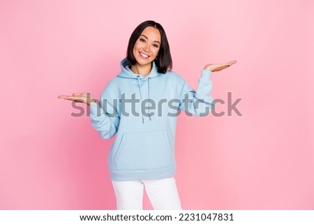 Photo portrait of pretty young lady palms showing scales advantage products dressed stylish blue outfit isolated on pink color background