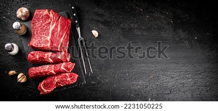 Pieces of raw beef on a stone board. On a black background. High quality photo Royalty-Free Stock Photo #2231050225
