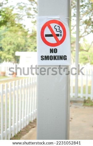 No smoke sign on a tree at public park.
