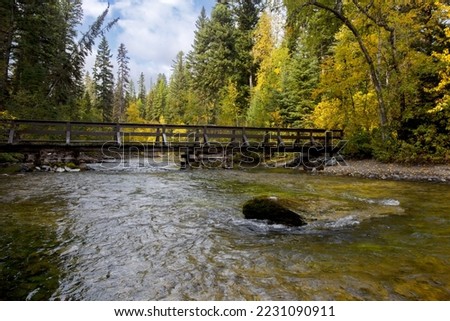 Simple, rustic wood bridge over Kintla Creek in Glacier National Park at Kintla Lake area creates tranquil forest and water scenic in Montana Royalty-Free Stock Photo #2231090911