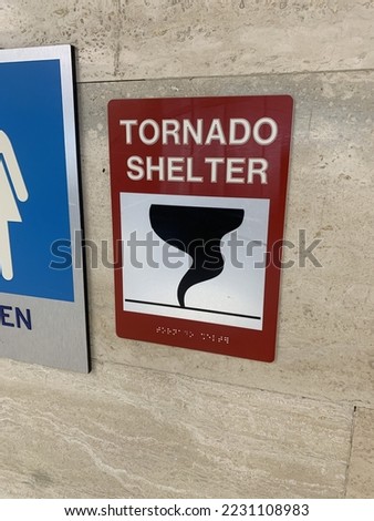 A sign directs travelers in an airport where to seek shelter in the event of a tornado
