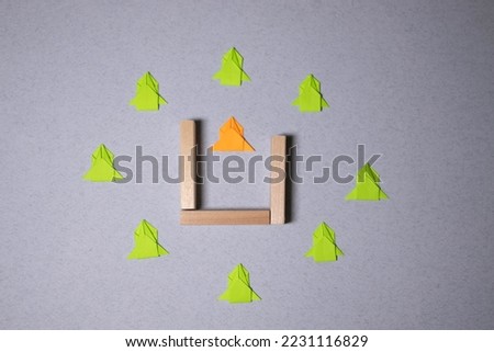 Think different concept, hand holding green paper arrow on wooden background.