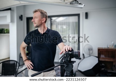 Ambitious confident Portrait of a male camera operator or photographer with a camera on a tripod for video shooting. Looking to the left