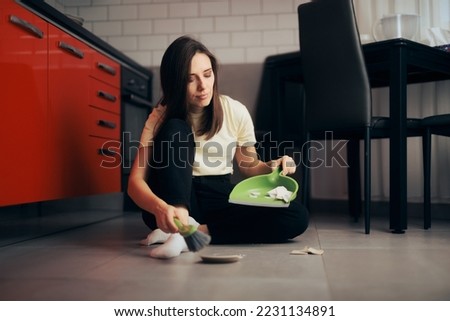 
Unhappy Woman Cleaning up After Broken Plate Incident. Sad girl having an accident in the kitchen 
 Royalty-Free Stock Photo #2231134891