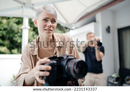 Beautiful confident female videographer shoots a movie on camera.