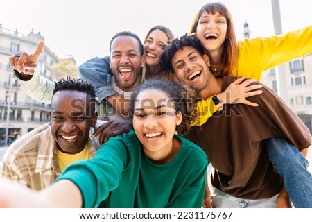 Young group of happy multiracial friends taking selfie portrait in the city. United millennial people laughing and enjoying time together outdoor. Happiness and friendship concept