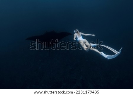 Woman freediver with white fins swim with manta ray. Freediving with big manta ray Royalty-Free Stock Photo #2231179435