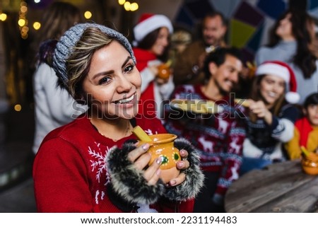 Hispanic young woman portrait holding a cup of fruit punch at traditional posada party for Christmas in Mexico Latin America