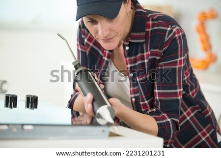 a woman is repairing kitchen Royalty-Free Stock Photo #2231201231