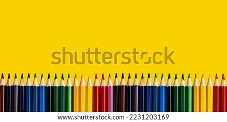 Colored pencils border on yellow background. Banner with copy space with multicoloured supplies, drawing tools.