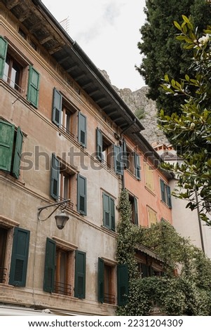 Old historic Italian architecture. Traditional European village rustic buildings. Flowers, wooden windows, shutters and pastel walls. Aesthetic summer vacation travel background