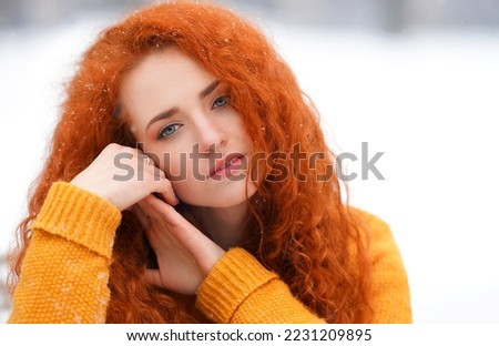                   Portrait of a young tender red-haired girl on the street, looking at the camera. Background             