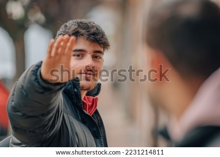 young man in the street waving Royalty-Free Stock Photo #2231214811