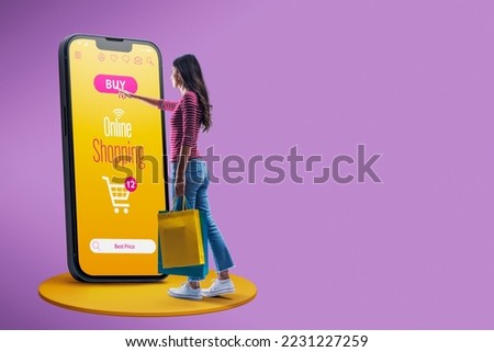Happy woman doing online shopping using a big smartphone, she is holding shopping bags and touching the buy button on the screen Royalty-Free Stock Photo #2231227259