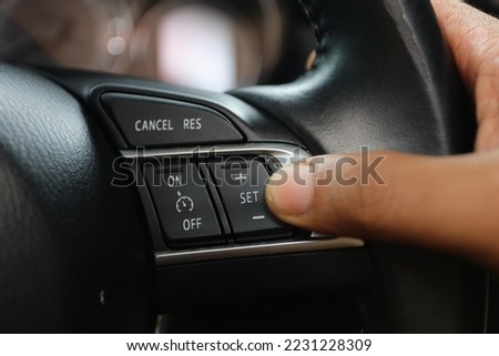 the driver's hand presses the cancel button to set the cruise control feature on modern cars.  cruise control button on the steering wheel of a luxury car