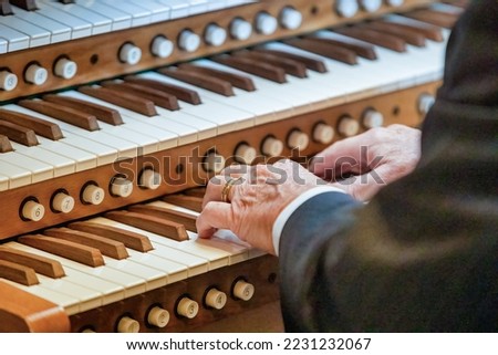 Close- up of a men's hands playing a three-manual church organ. Musical education concept.