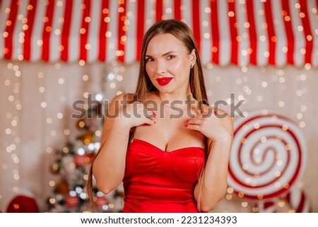 Beautiful young woman with long hair in red evening dress is posing in white room with Christmas decoration. Beauty fashion concept. Royalty-Free Stock Photo #2231234393