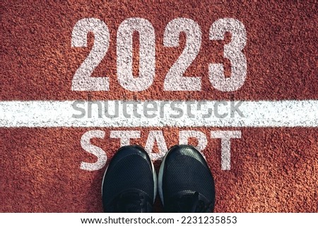 Start 2023 year concept, top view of man shoe on an athletics track engraved with the year 2023.Start of the new year 2023, goals and plans for the next year.Opportunity, challenge,Goal of Success Royalty-Free Stock Photo #2231235853
