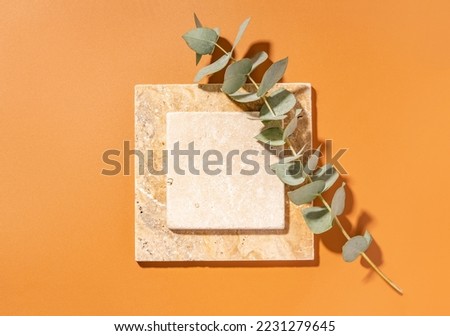 Travertine tiles. Empty square mockup template for product presentation made with natural travertine and eucalyptus on a yellow background. Flat lay with copy space. Top view.
