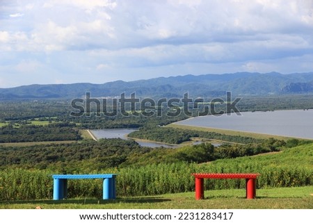 Panoramic picture. Below is a large pond with bright bluesky and clouds background and trees naturally.