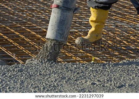 Construction worker pours concrete on rebar using concrete pump Royalty-Free Stock Photo #2231297039