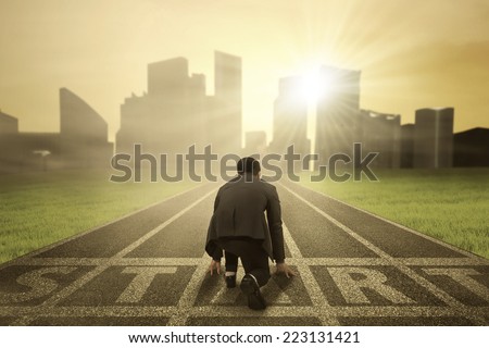 Rear view of business person in ready position on start line to compete Royalty-Free Stock Photo #223131421