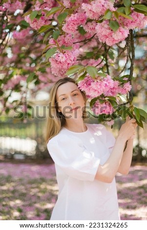 White european girl in white blouse under sakura blossom