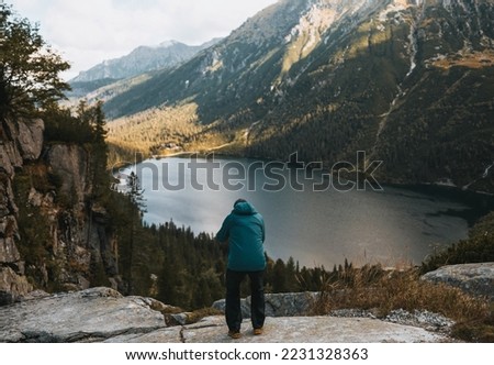 Photographer is taking photos of beautiful mountain nature with the lake. Travel and active lifestyle concept.Young man photographer taking photographs with a digital mirrorless camera in a mountains