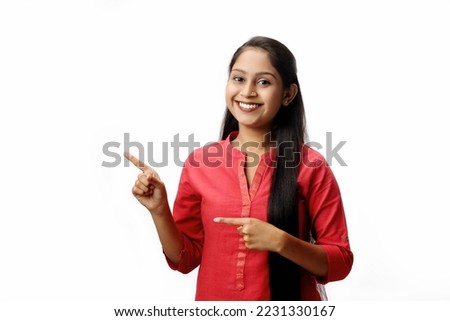 Indian girl smiling and showing something looking towards camera isolated on white background  Royalty-Free Stock Photo #2231330167