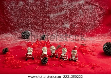 5 santa claus figures made of sugar paste in christmas concept with snow effect and cones on red background. christmas themed image