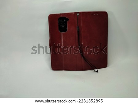 brown smartphone case with texture on the strap and smartphone camera isolated on white background