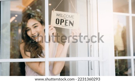 Woman setting open sign board through the door glass., Owner of a small business changing the sign for the reopening.