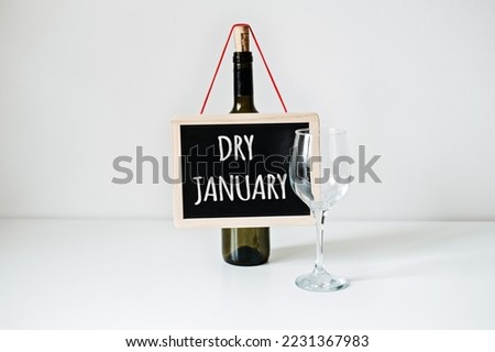 Dry January. Alcohol-free challenge, Health campaign urging people to abstain from alcohol for the January month. Bottle of wine, glass and sign with text Dry January Royalty-Free Stock Photo #2231367983