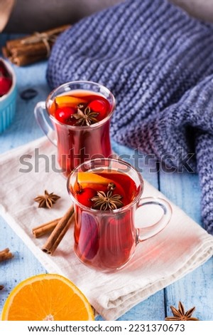 Homemade hot mulled wine with orange, cinnamon and berries in glasses on the table. Vertical view