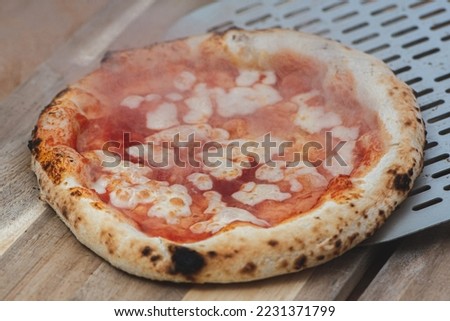 Serving hot pizza Margherita with tomato sauce and mozzarella with a shovel on a wooden board, with smoke