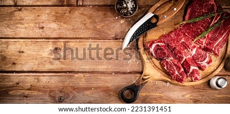 Raw beef on a cutting board with rosemary and spices. On a wooden background. High quality photo