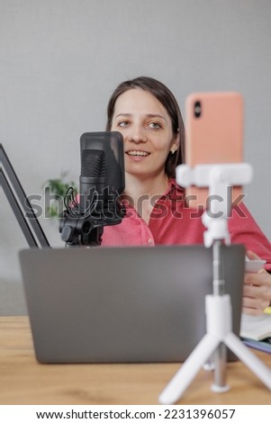 female musician and podcaster creates audio and video content for social media. a confident European woman speaks into a microphone and records a lesson or interview. streaming and working online on