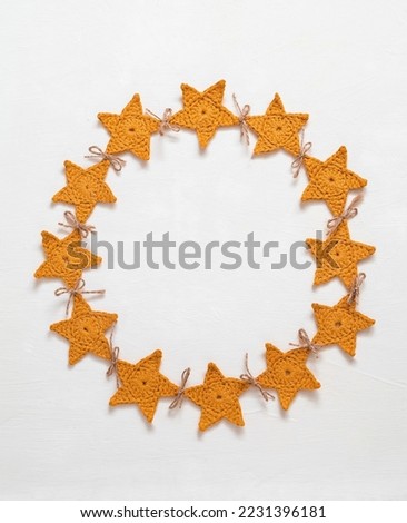 Christmas background with copy space. Decorative frame of handmade crochet yellow star garland on a white background. Top view.