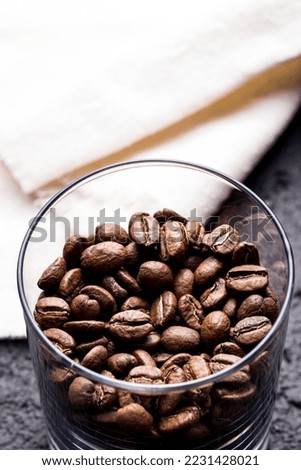 Roasted coffee beans in glass container, on dark background, closeup image, space for text