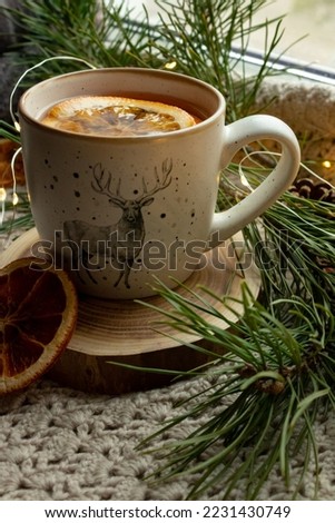 A cup of green tea, dried orange on a knitted, fabric rug, pine needles branches, New Year's atmosphere Royalty-Free Stock Photo #2231430749