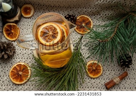 Green tea in a cup on a fabric mat, Christmas fir branches on the table, dried oranges, citrus fruits
