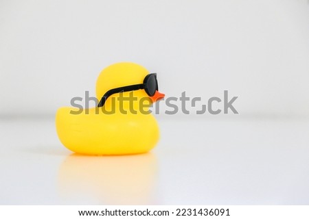 Cool yellow rubber duck wearing black sunglasses facing rightwards, copy space on the right.