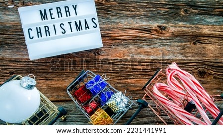Push cart with Christmas gifts and lightbox with wish on rustic table from above