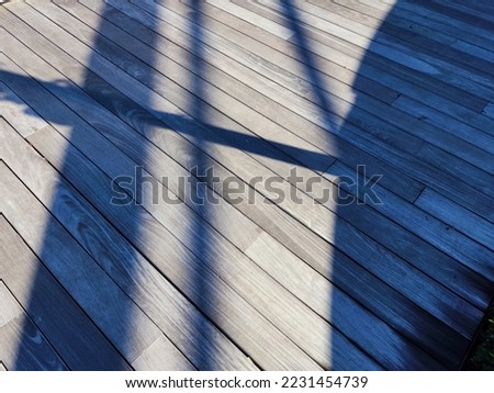 This is a picture of shadows being casted onto a boardwalk, creating interesting patterns and textures.